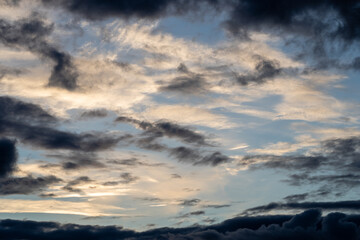 Bright blue cool autumn sky with light airy transparent clouds where some dark dramatic clouds create an eerie landscape
