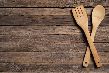 Crossed wooden spoon and fork on a background of old rustic wooden slats, copy space.