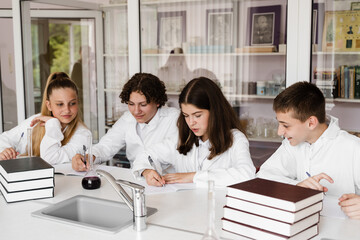 School education. Cheerful classmates in chemistry lesson hold flasks with liquid for experiments. Happy friends study together in class in laboratory.