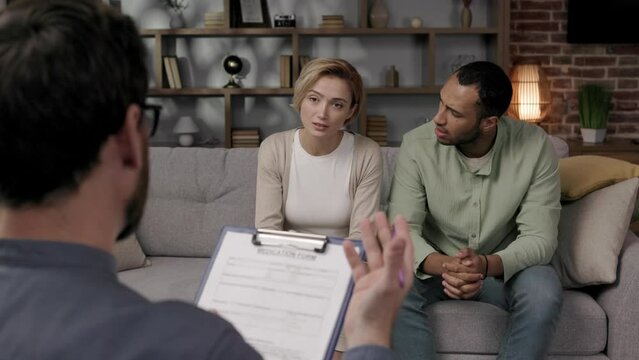 Multiracial quarrel between husband and wife at a session with a psychotherapist. A visit to a family psychologist for a married couple. A doctor consults an unhappy married couple. Help psychologist.
