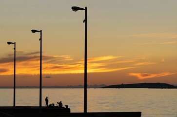 Silhouettes of street lights and fishermen on the beach of Sardinia, Italy, at sunset