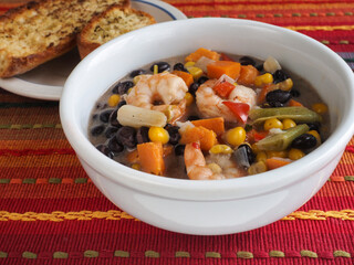 Bean and Shrimp Chowder in White Bowl Against Red
