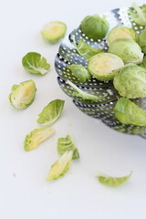Sliced pieces of raw Brussels sprouts on a silver plate, composition on a white background, healthy diet concept, healthy food,  vegetarian / vegan diet, cooking magazine, cookbook.