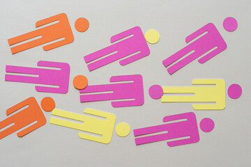 orange, pink, and yellow paper stick figure glyphs on blank paper