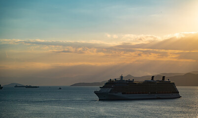 Fototapeta na wymiar luxury cruise ships passing by island during golden sunset. Travel, voyage and vacation concept