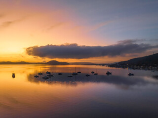 Sunrise over the water with fog, boats, clouds and reflections