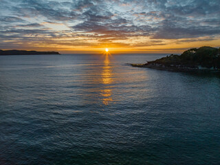 Naklejka premium Aerial sunrise seascape with calm seas and a mix of low and medium clouds
