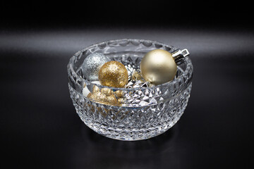 Macro abstract defocused view of a beautiful small crystal bowl with sparkling glitter holiday balls, with dark background