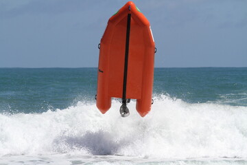 Orange inflatable surf rescue boat capsizes
