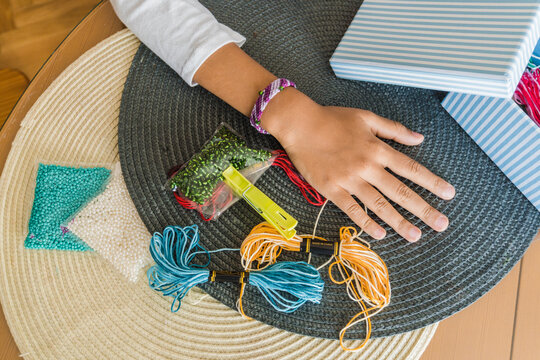 Hands of a kid with threads bracelets and materials
