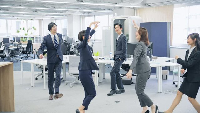 オフィスでダンスする会社員グループ