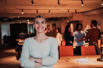 Portrait photo of a modern blonde on a break from work in a modern office. In the background, the team working on the projects