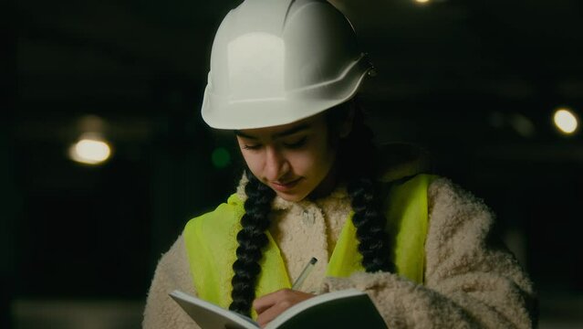 Young professional technical engineer constructor female builder architect woman in uniform stand on parking write notes think business plan for construction writting checklist engineering measures