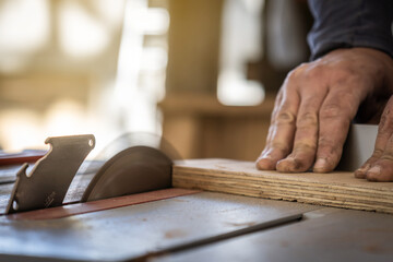 Carpenter cutting wooden board at his workshop.