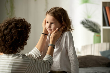 Loving mother stroking her little son and telling the words of support to him while they sitting in...