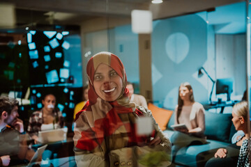 An older Muslim businesswoman presents a project to a young diverse team of people in a modern office