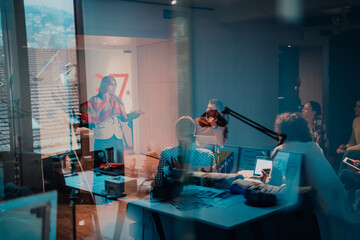 An older Muslim businesswoman presents a project to a young diverse team of people in a modern office