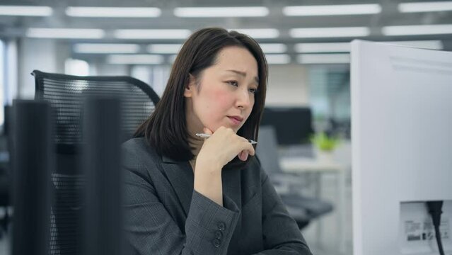 パソコン画面を見ながら悩む女性会社員