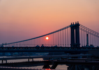 Manhattan bridge at dusk and setting sun disc
