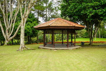 Fototapeta na wymiar A gazebo for rest and shelter in a very large garden of grass and flowers. Thriving meadow. Taman Bunga Nusantara, Cianjur, West Java, Indonesia.