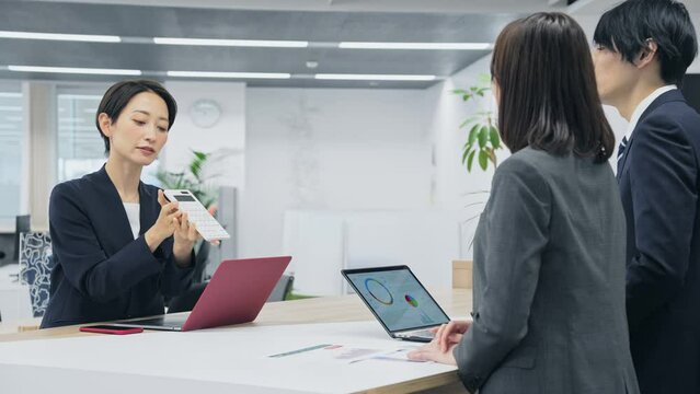 電卓を見せて交渉するビジネスグループ