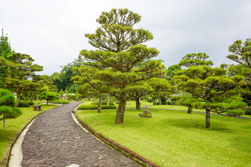 A walkway in a garden made of brick traverses the edge and amidst lawn or meadow in a flower garden. 
Tourist, travel, holiday and vacation spot Taman Bunga Nusantara, Cianjur, Indonesia
