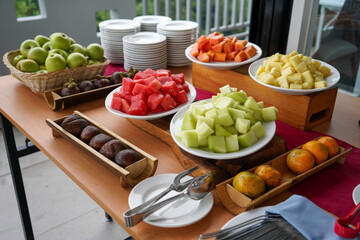 Dessert breakfast in a buffet style consisting of pieces of watermelon, melon, papaya, pineapple, 
apple, orange, salak, snakefruit, pineapple sliced ​​into small pieces on a white plate.