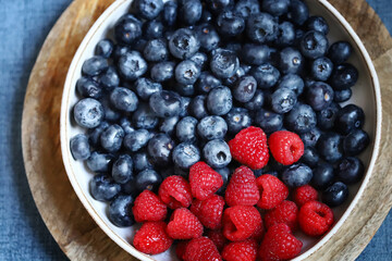 Fresh selected raspberries and blueberries in a bowl. Healthy snack. Berries for dessert. Close-up.