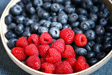 Fresh selected raspberries and blueberries in a bowl. Healthy snack. Berries for dessert. Close-up.