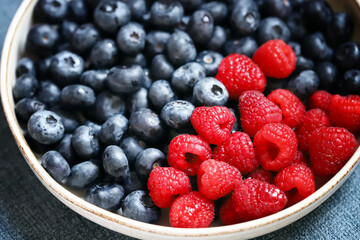 Fresh selected raspberries and blueberries in a bowl. Healthy snack. Berries for dessert. Close-up.