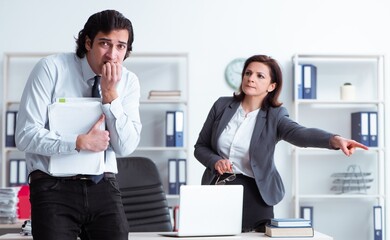 Old female boss and young male employee in the office