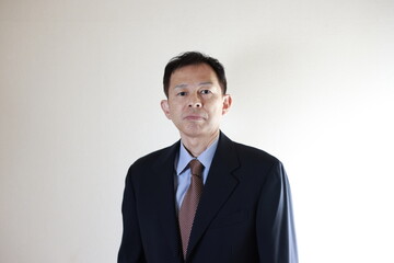 Middle-aged Japanese male businessman wearing navy blue suit on white background. Conceptual image of a project proposal, strategic business success and negotiation closing.