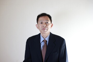 Middle-aged Japanese male businessman wearing navy blue suit on white background. Conceptual image of a project proposal, strategic business success and negotiation closing.