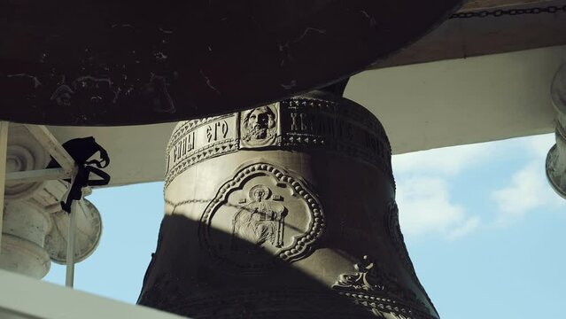 The main largest bell in the center and smaller around the edges on the belfry of the Russian Orthodox Church, the hand strokes the surface of the bell, which is still gently vibrating