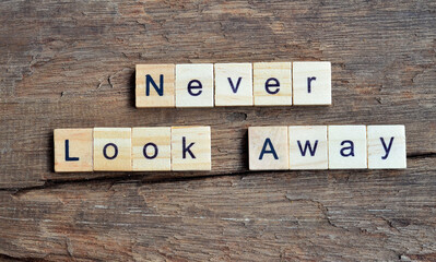 Never Look Away text on wooden square, business inspiration quotes