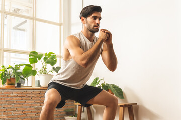 Obraz premium Handsome fitness caucasian young man, guy wearing sportswear training strength muscles workout, cardio exercise training in living room at home for healthy body strong athletic, fit active lifestyle