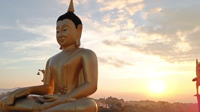 Side view Golden Buddha statue against sunset sky in Thailand temple
