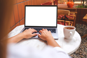 Mockup image of a woman using and typing on laptop computer with blank white desktop screen while drinking coffee