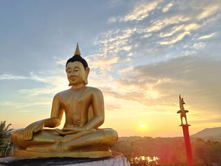 Beautiful Golden Buddha statue against sunset sky in Thailand temple