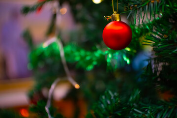 Close up shot of outdoor decorated Christmas tree with bright red balls on blurred fairy background. blurry steering lights Bokeh effect.