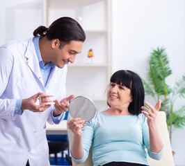 Old woman visiting young doctor dentist