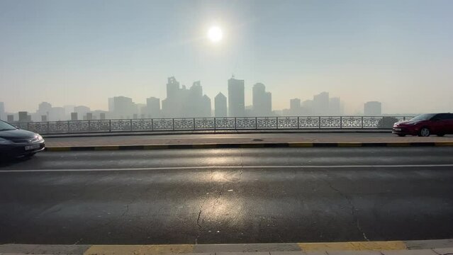 Vehicles passing on Sharjah Khalid lake bridge at sunrise, United Arab Emirates.