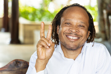 Happy smiling African man pointing up 2 fingers, v for victory gesture