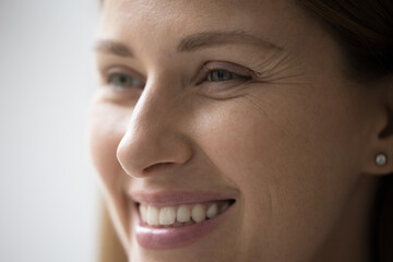 Cropped close up part of female face, happy young Caucasian woman portrait look aside, having...