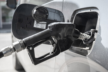 Refuel gasoline or diesel oil into the car fuel tank, close-up and selective focus at the nozzle...