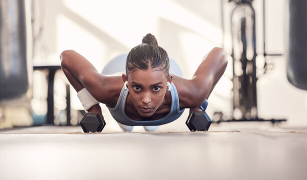 Dumbbell, fitness and black woman training, workout or bodybuilder in gym floor portrait for body goals, muscle and wellness motivation. Strong, power and sports girl doing push up exercise with gear