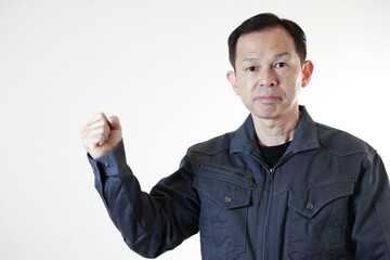 Fototapeta premium Middle-aged Japanese male worker wearing gray work clothes on white background with hands folded. Concept image of high technology in manufacturing, process work instructions, and working environment.