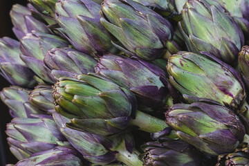 Close up of raw fresh Globe Artichokes on a greengrocers stall at a food market 