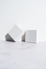 Two white square gift boxes mockup on gray concrete background. Closeup, shadows, minimalist concept