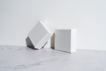 Two white square gift boxes mockup on gray concrete background. Closeup, shadows, minimalist concept